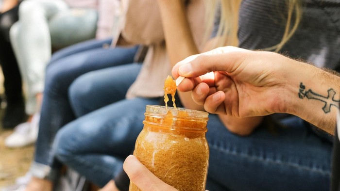 Eine Person hält ein Glas mit einer Flüssigkeit, während jemand anderes hineingreift.