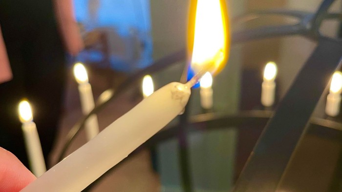 En person tænder lys på en kandelev.