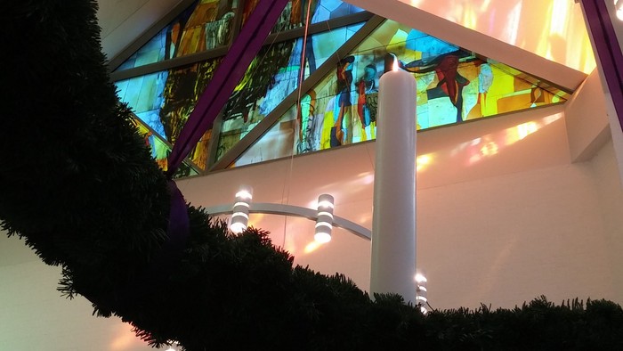 En julekrans med lys og en lysstake i et indendørs areal