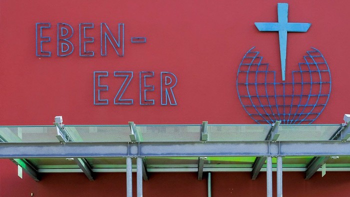 Vier Personen stehen vor einem Gebäude mit dem Namen Eben-Ezer.