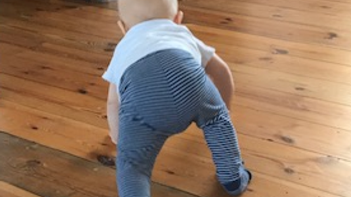 Ein Baby krabbelt auf einem Holzboden.