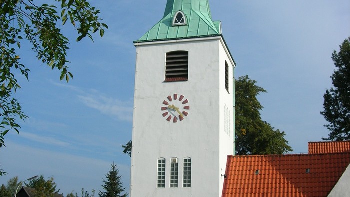 Weiße Kirche mit grünem Turm und roter Uhr