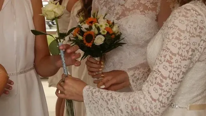 To brudgommer holder hånd i hånd og viser deres bryllupsringer