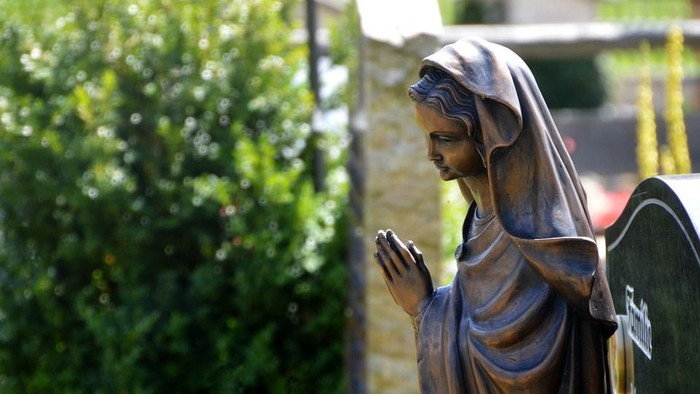 Die Statue einer betenden Frau mit Flügeln im Garten.