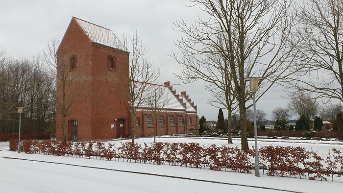 En rød murstensbygning og en træ i sne.