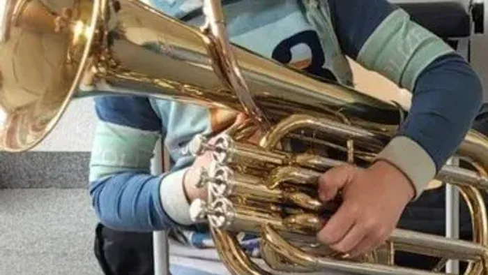 Ein Kind spielt eine Posaune in einem Raum.