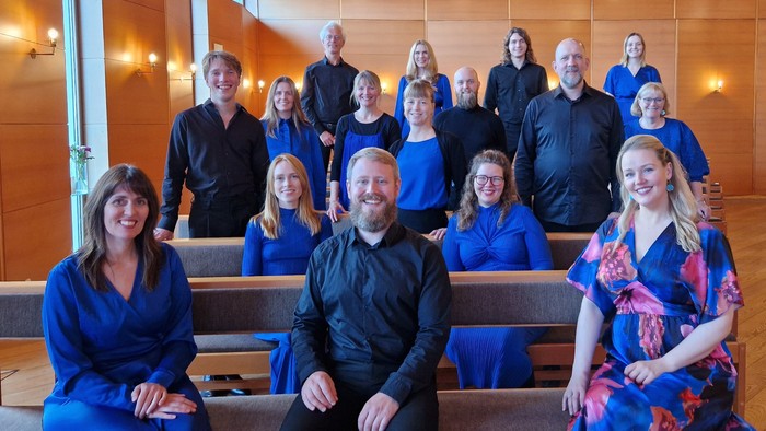 En gruppe af mennesker poser i en kirke, alle klædt i blå.