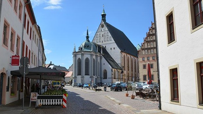Historische Kirche in kleiner Stadt mit Kopfsteinpflasterstraße und Gebäuden