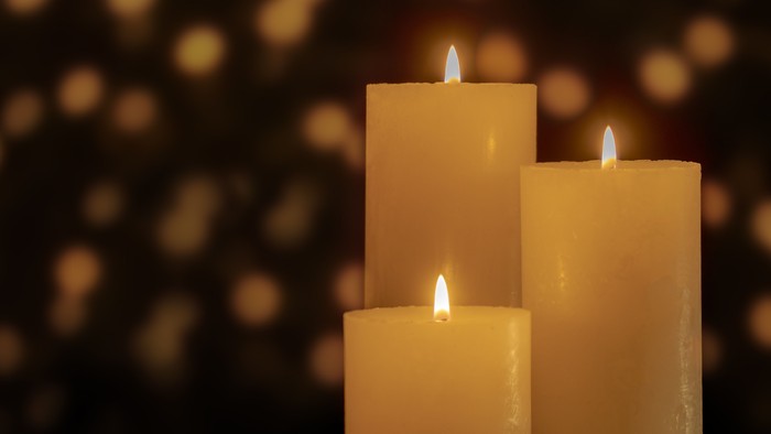 Tre lysende lysekander på en mørk baggrund med glimrende lysepunkter.