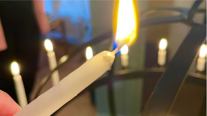 En person tænder lys på en række lysekøn.
