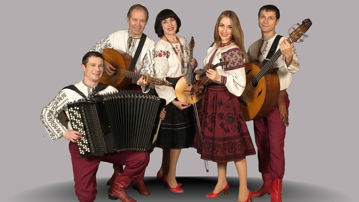 En gruppe af musikanere i tradisjonelle klæder spiller forskellige instrumenter.