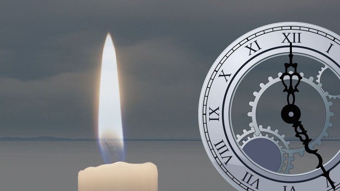 En lysende lyse med en klokke i mørkt himmel.