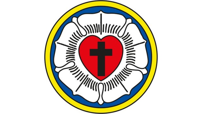 Herz mit Kreuz in weißem Rosette, blauem und gelbem Kreis