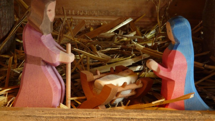 Eine Krippe mit Holzfiguren, Maria, Josef und Baby Jesus in einer Stallung.