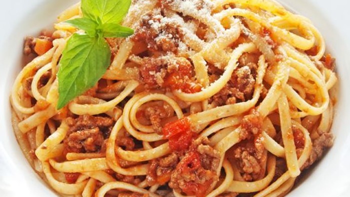 En ret med spaghetti i kødsaus med parmesan og basilika.