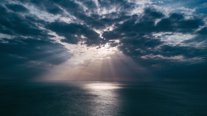 En dramatisk skyer og solstråler over havet