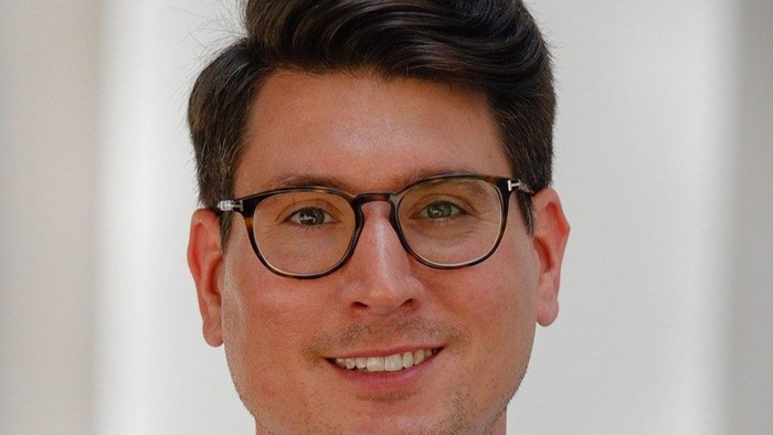 Ein Mann mit Brille und dunklem Haar lächelt in die Kamera.