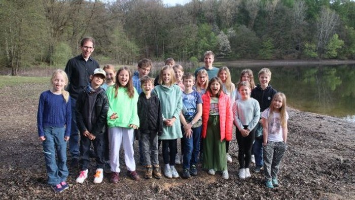 Eine Gruppe von Menschen posiert vor einem Waldsee