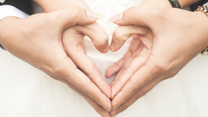 En bryllupspar med håndene dannet som et hjerte.