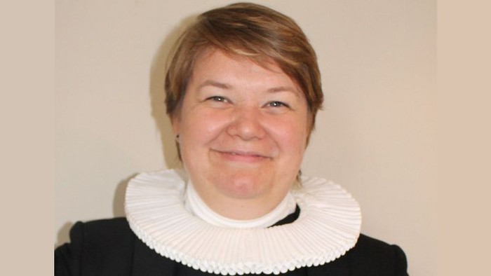 En kvinde med kort hår og en hvid krage.