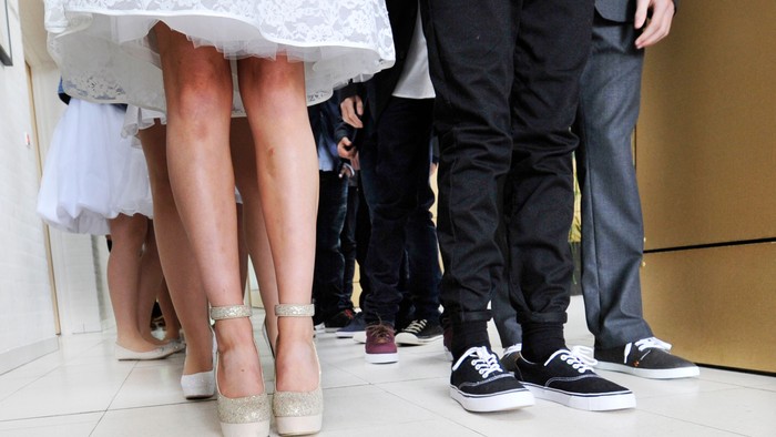 En brud og to mænd står i en kreds, deres ben og sko er synlige.