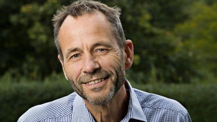 En middlealder mand med kort hår og skæg, smilende og ser direkte i kameraet.