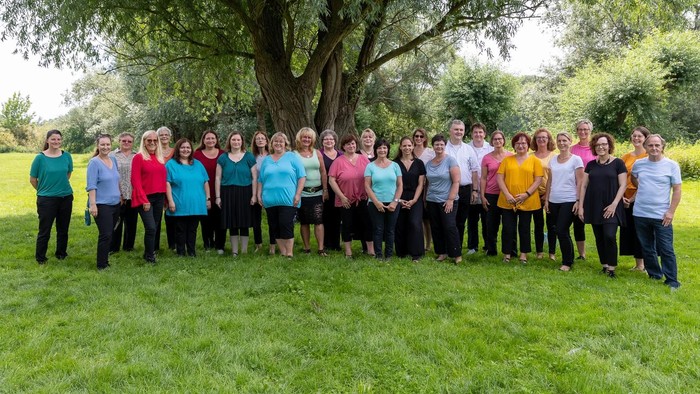 Eine Gruppe von Frauen posiert vor einem Baum auf einer Wiese