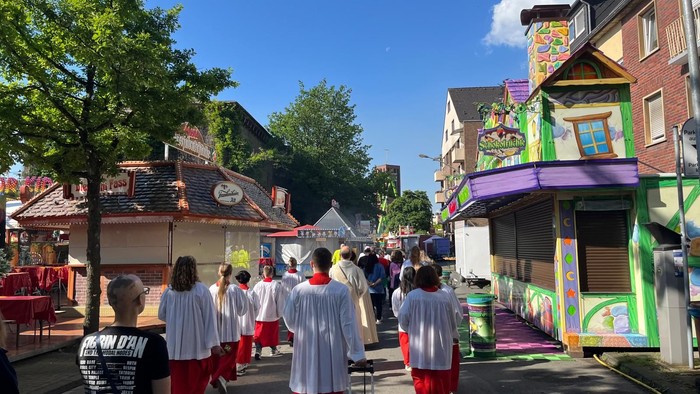 Eine Gruppe von Menschen in weißen und roten Kleidern marschiert durch eine farbenfrohe Straße.