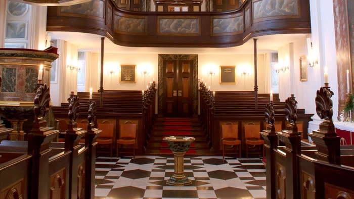 Indre del af en stor og præget kirke med høje vægge og malede dekorationer.