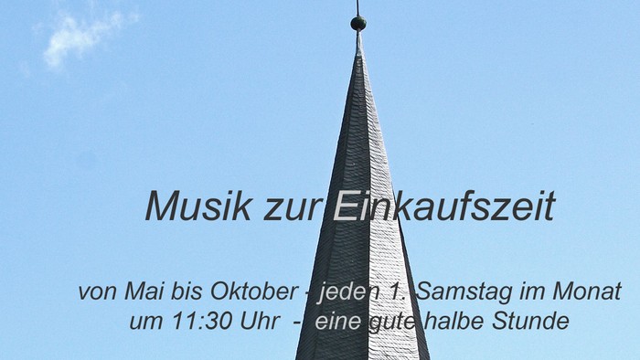 Das Bild zeigt einen hohen Kirchturm vor einem klaren blauen Himmel.