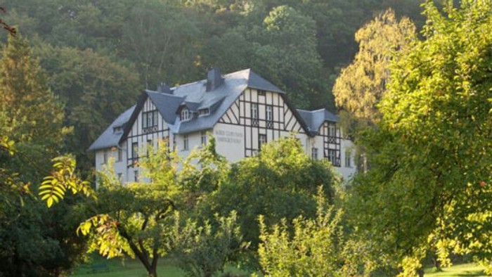 Großes, malerisches Gasthaus umgeben von üppigem Grün und Bäumen