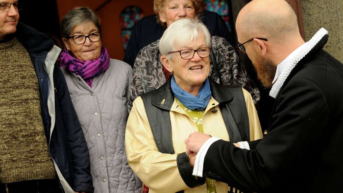 En mand håndklæder en ældre kvinde, mens andre ser til.