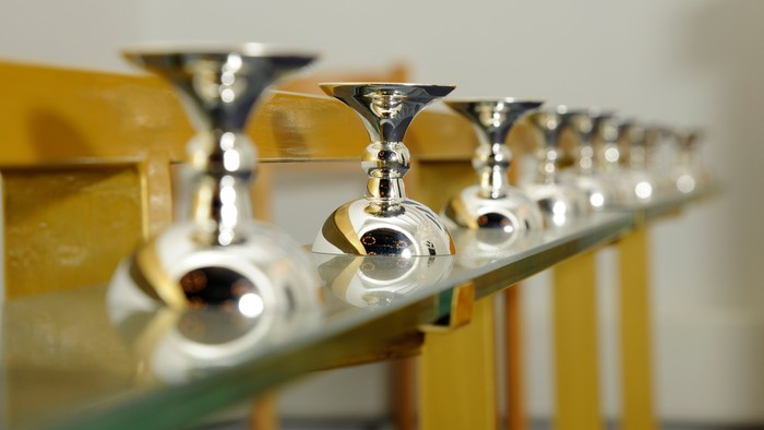 En rekke sølvfarvede vandkraner monteret på en gul trævæg