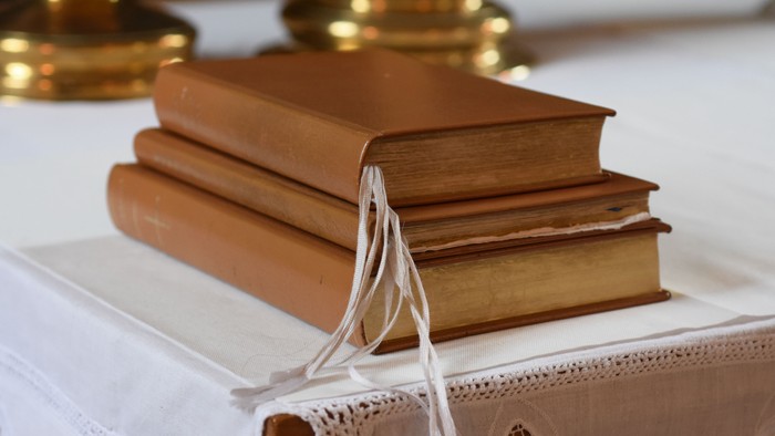 To boger ligger på en hvid duk med guldramme.