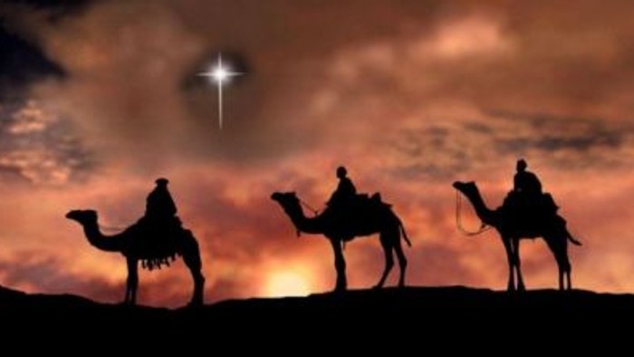 Tre kameler med ridere mod solnedgang og stjernetåge