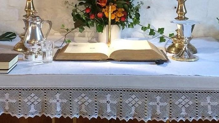 Bordet er dekket med en hvid duk og har blomster, bøger og teekanner på.