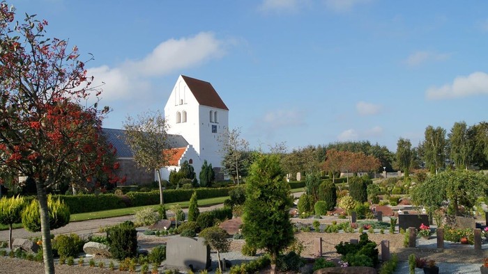 En smuk have med en hvid bygning og en del forskellige planter og træer