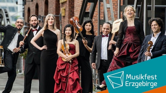 Ein Orchester posiert vor einem Backsteingebäude bei einem Musikfestival