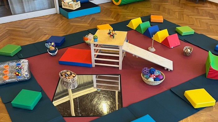 Bunter Spielplatz mit Rutsche und Kissen auf Holzboden