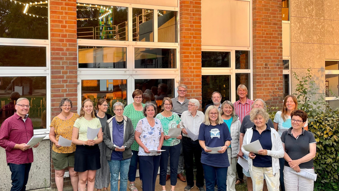Eine Gruppe von Menschen steht vor einem Gebäude und hält Bücher.