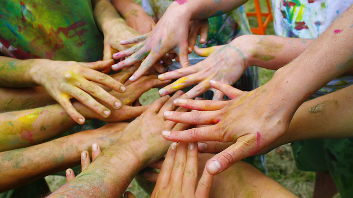 Mehrere Hände mit bunten Farben verschränkt