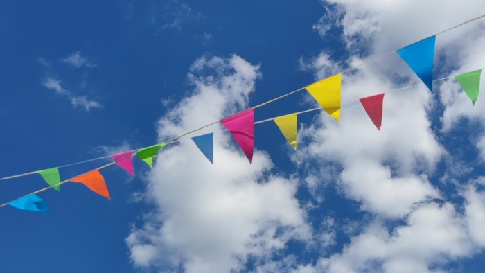Bunte Fähnchen im blauen Himmel mit Wolken