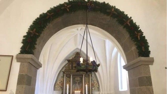 En kirkeindgang med juldekorationer og alter.