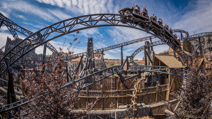 Ein großer Achterbahnwagen fährt durch eine Holzkonstruktion bei klarem Himmel.