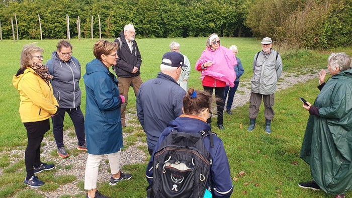 En gruppe af folk står i en park og snakker med hinanden.