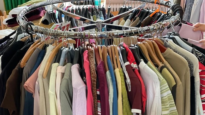 Ein Kleiderbügel mit vielen farbenfrohen Hemden und Pullovern