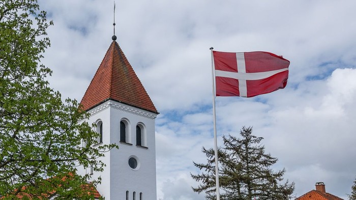Tårn med klokke og dansk flag på en klar dag