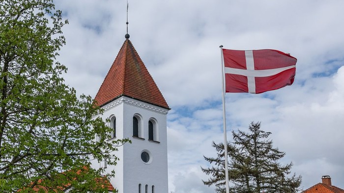 Tårn med klokke og dansk flag på en klar dag
