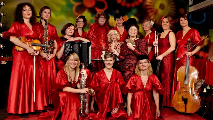 En gruppe kvinder i røde kjoler spiller musikinstrumenter