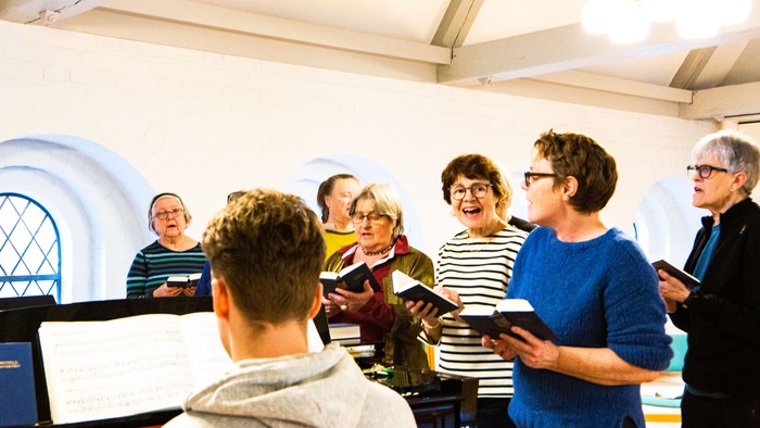 En gruppe af mennesker står sammen og synger i en kirke.